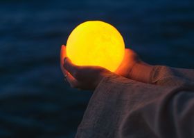 A luminous hand holding a glowing orb in deep space